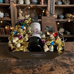 Gavekurv til jul: Flot julegavekurv med spansk Camina r�dvin, chokoladekugler og bl�de karameller, fotograferet i hyggelig decemberstemning med gran og julepynt i baggrunden