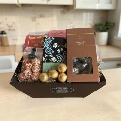 Gavekurv med chokolade og kaffe: Pr�sentabelt milj�billede af den �bne luksuskurv, fotograferet p� et lyst k�kkenbord for at fremh�ve de stilrene m�rkevareemballager.