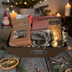 Gavekurv til jul: Flot julegavekurv sp�kket med chokolade, lakrids og s�de sager, fotograferet i hyggelig decemberstemning med julepynt og gran i baggrunden.