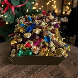 Gavekurv til jul og fest: Flot julegavekurv sp�kket med chokoladekugler og gyldne hjerter, fotograferet i hyggelig decemberstemning med julepynt og gran i baggrunden.